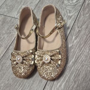 sparkly, gold-colored low-heel Mary Jane shoes with bow embellishments. Size 35E